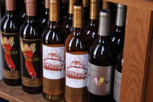 Wine bottles on a shelf featuring Quady Essensia Orange Muscat, Quady Elysium, and Quady Red Electra