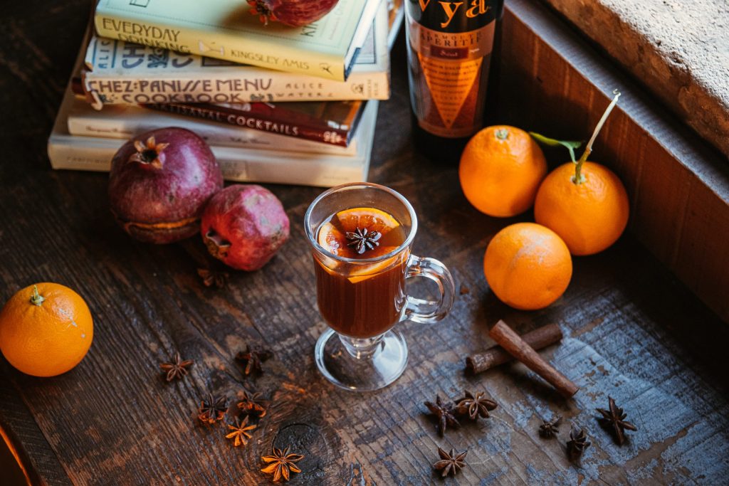 Mulled Wine Cocktail with books, cinnamon, star anise, oranges, pomegranates, and Vya Sweet Vermouth
