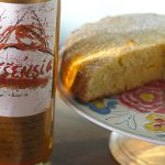 Essensia cake on a platter next to a bottle and glass off Essensia Orange Muscat sweet dessert wine.