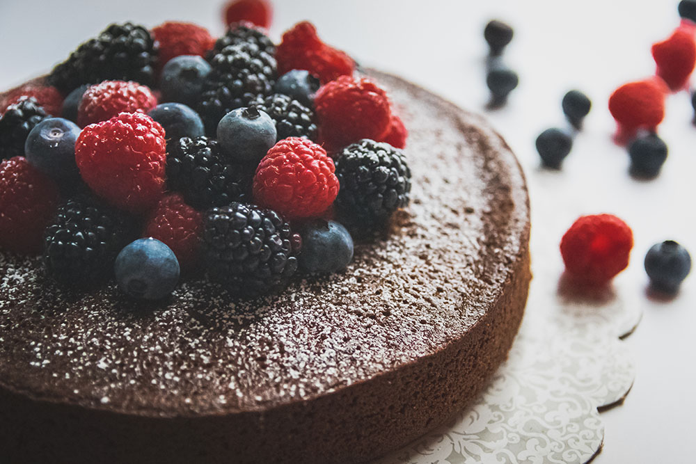 Triple Chocolate Port Wine Cake topped with berries and powdered sugar