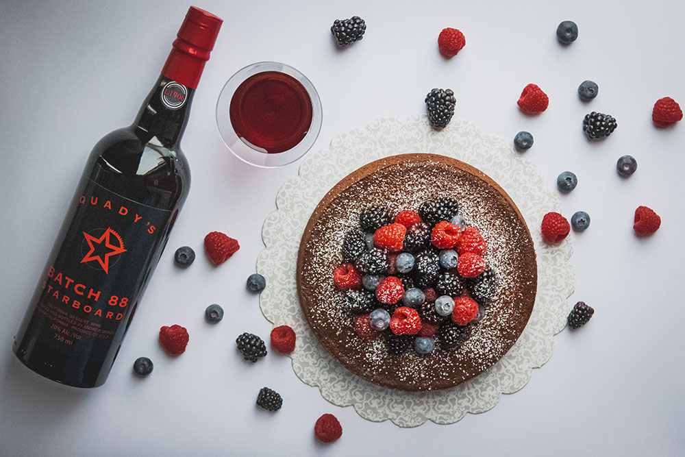 Bottle of Starboard Batch 88 with Port Chocolate Cake, a glass of Starboard port wine, and berries