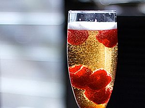 Socialite cocktail with raspberries floating inside champagne flute filled with vya vermouth and sparkling wine.