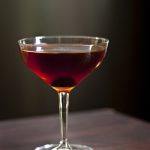 Manhattan cocktail in a coupe glass with a maraschino cherry.