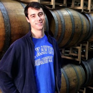 Cole Dennis standing in front of wine barrels