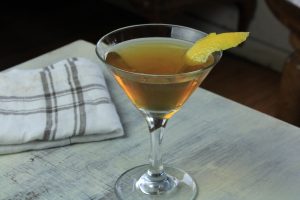 Wet Manhattan cocktail in a martini glass and a lemon peel garnish.