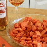 a dish of Quady Essensia Orange muscat yams next to a glass of wine and a bottle of Quady Essensia Orange Muscat Wine