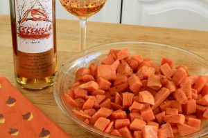 a dish of Quady Essensia Orange muscat yams next to a glass of wine and a bottle of Quady Essensia Orange Muscat Wine