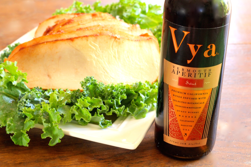 Slices of Vya Sweet Vermouth brined turkey next to a bottle of Vya Sweet Vermouth.