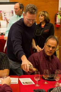 Winemaker Darin Peterson Pouring Essensia Orange Muscat Sweet Dessert Wine to and attendee at Quady Winery's Wine Club Holiday Party in Madera, California.