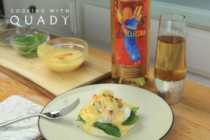 Crab benedict breakfast dish next bowls of toppings and a bottle and glass filled with Electra Moscato sweet wine.