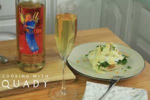 Crab benedict breakfast dish next to a bottle and champagne flute filled with Electra Moscato sweet wine.