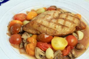 Grilled chicken breast on top of tomatoes, mushrooms, onions and garlic.