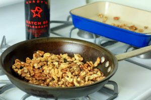 Walnuts, butter and sugar in a pan with a bottle of Starboard Batch 88 in the background.
