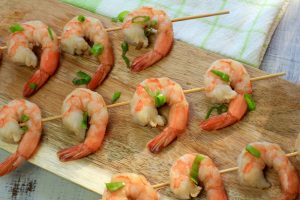 Cooked shrimp on skewers with green onion.