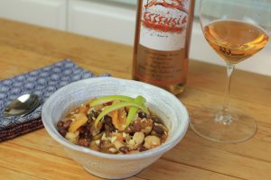 Bowl of chili next to a bottle and glass of Essensia Orange Muscat dessert wine.