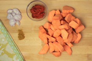 Sweet potato, curry and shallots on a cutting board.