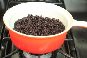 Black rice being cooked in a pot.