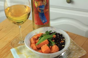 Bowl of sweet potato curry on a table with a bottle and glass of Electra Moscato wine behind it.