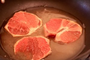 Slicers of grapefruit simmering in a pan with Deviation dessert wine and sugar.