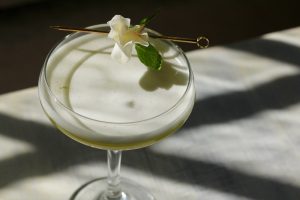 Spring cocktail in a coupe glass with an edible flower garnish.
