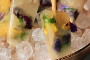 Electra Moscato wine frozen popsicles filled with edible flowers in a bowl of ice.