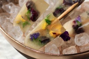 Electra Moscato wine frozen popsicles filled with edible flowers in a bowl of ice.