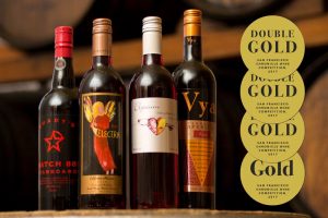 Starboard Batch 88 port wine, Electra Moscato wine, Elysium Black Muscat dessert wine and Vya Sweet Vermouth sitting on a wine barrel with double gold and gold medals present.