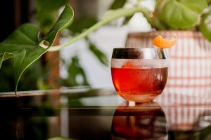 The Vya Negroni with an orange twist and a plant in the background