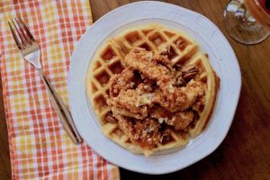 Fried chicken over waffles with syrup and pecans.