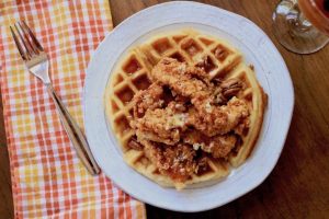 Fried chicken over waffles with syrup and pecans.