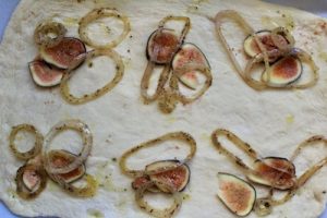 Sliced figs and onions on flat bread dough.