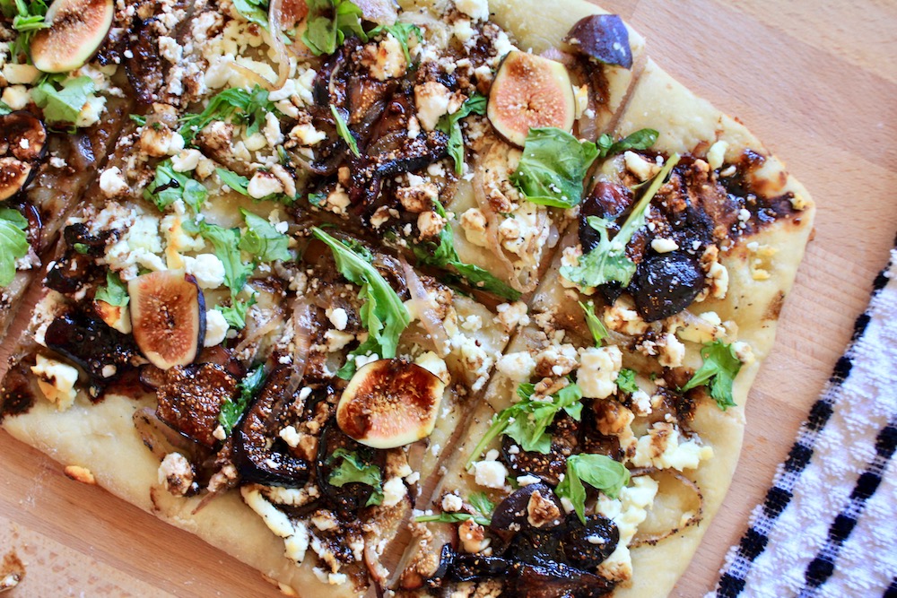 Baked fig and arugula flat bread cut into pieces.