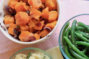 Sweet potato dish next to green beans and mashed potatoes.