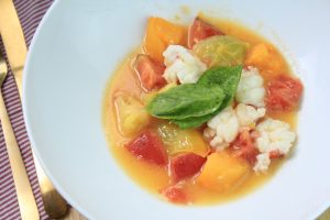 Butter poached Lobster dish with heirloom tomatos and basil in a bowl.