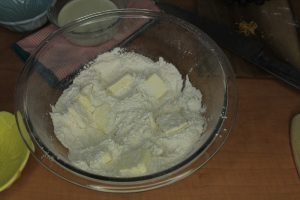 Flour mixture in a bowl with lumps of butter inside.