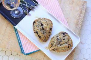 Two blueberry scones on a dish with lavender next to a glass of Electra Moscato wine.