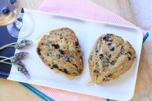 Two blueberry scones on a dish with lavender next to a glass of Electra Moscato wine.