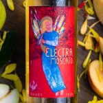 Close up of Electra Moscato bottle label with peaches, flowers and pears on both sides of it.