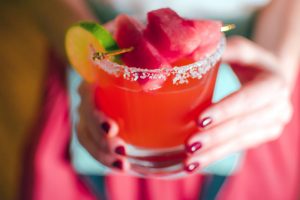 Two hands holding a Quady Red Electra Moscato watermelon margarita cocktail