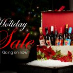 "Holiday Sale, Going on now," text overlaid on a picture of a Christmas tree and holiday gift box filled with Quady sweet wines.