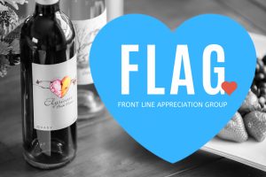 Black and white photo of Elysium Black Muscat on a table next to fresh fruit with a blue heard graphic and text overlay, "FLAG, Front Line Appreciation Group."