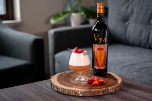 Sweet and sour cocktail created by Beautiful Booze sitting on a coffee table next to a bottle of Vya Sweet Vermouth.