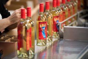 Bottle of the Electra Moscato wine coming off of the bottling line and being hand packed into cases.