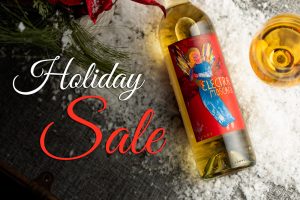 Holiday wine sale banner with a bottle of Electra Moscato lying on a table in snow with a filled wine glass next to it.