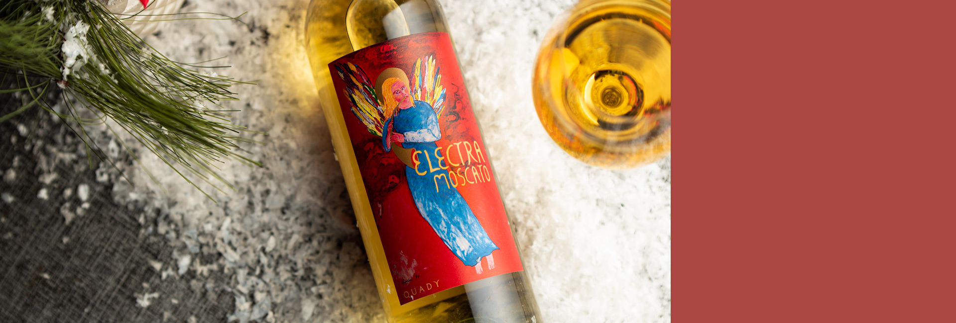 Holiday wine sale home page banner with a bottle of Electra Moscato lying on a table in snow with a filled wine glass next to it.