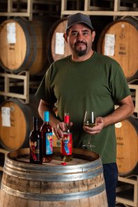 Daniel Martinez, General Winery Worker, holding a glass and bottle of Electra Moscato wine.