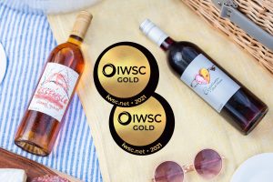 Two gold medals from the International Wine and Spirit Competition next to bottles of Essensia Orange Muscat dessert wine and Elysium Black Muscat dessert wine.