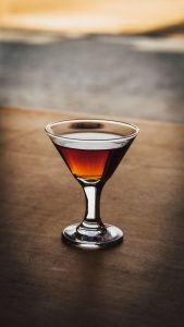 A glass sitting on top of a brown glass and the liquid is our vya sweet vermouth