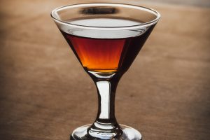 A Manhattan cocktail with vya vermouth sitting on a brown table