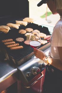 Woman sipping a glass of Red Electra Moscato while barbecuing burgers and brats